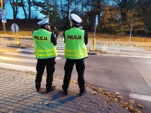 Policjanci stoją przy przejściu dla pieszych w rejonie cmantarza