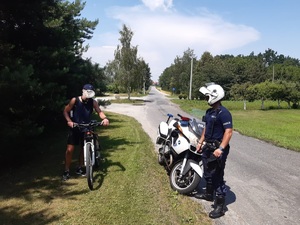 motocykl policyjny, policjant i mężczyzna z rowerem