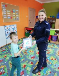 Policjantka przekazuje dziecku książeczkę o bezpieczeństwie