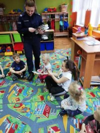Policjantka rozdaje książeczki dzieciom
