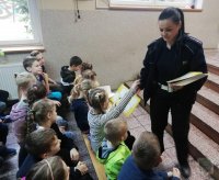 Policjantka rozdaje książeczki dzieciom