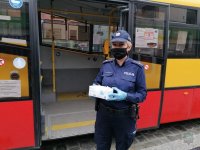 Policjantka stoi z maseczkami na przestanku