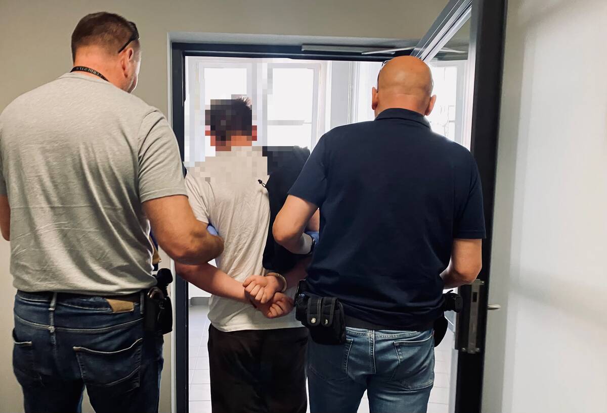 zdjęcie: Policjanci prowadzą zatrzymanego mężczyznę 