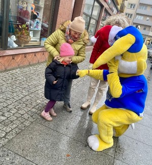 Policjanci rozdają odblaski z maskotką policyjną.