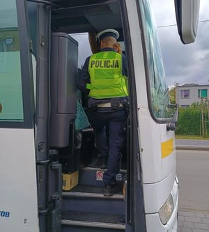Kolorowa grafika - policjant podczas kontroli autokaru.