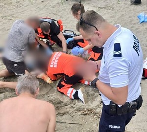 Policjant i strażacy udzielają pomocy.