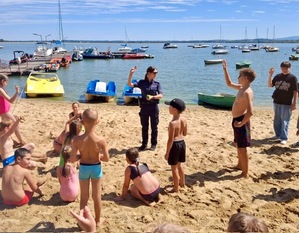 kolorowe zdjęcie - policjantka z dziećmi podczas spotkania nad jeziorem