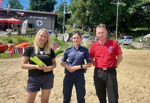 kolorowe zdjęcie - policjantka z dziećmi podczas spotkania nad jeziorem