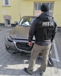 Policjant stoi przy zabezpieczonym aucie