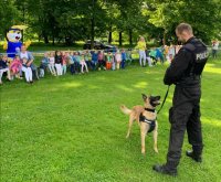 Policjant wraz z psem służbowym stoi przed dziećmi