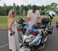 Na motocyklu policyjnym siedzi mały chłopiec obok niego stoją rodzice