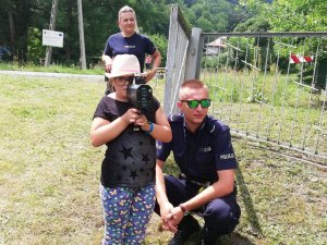 Na zdjęciu policjant kuca obok dziewczynki która przy oku trzyma radar policyjny