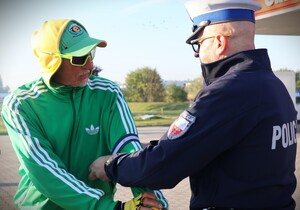 zdjęcie kolorowe: policjanci rozdają dzieciom kaski i elementy odblaskowe